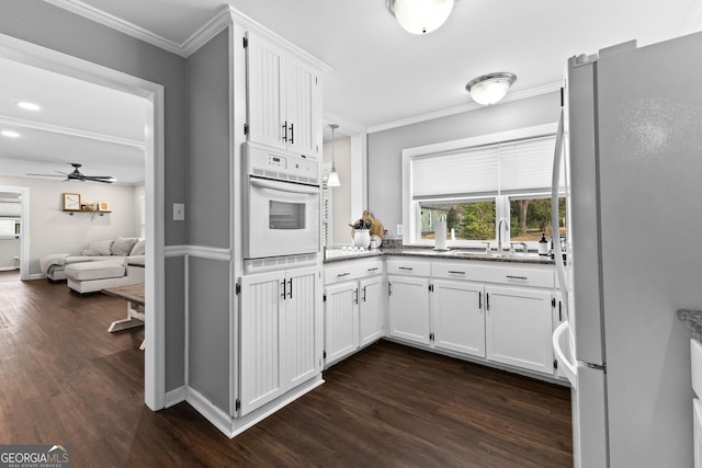 kitchen featuring white cabinetry, sink, hanging light fixtures, ornamental molding, and white appliances