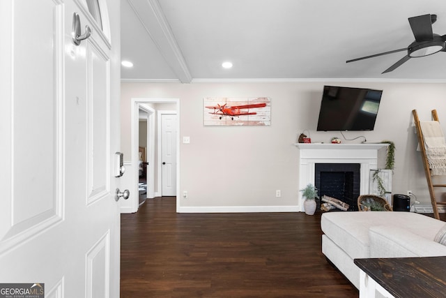 living room featuring ornamental molding, dark wood-type flooring, ceiling fan, and a fireplace