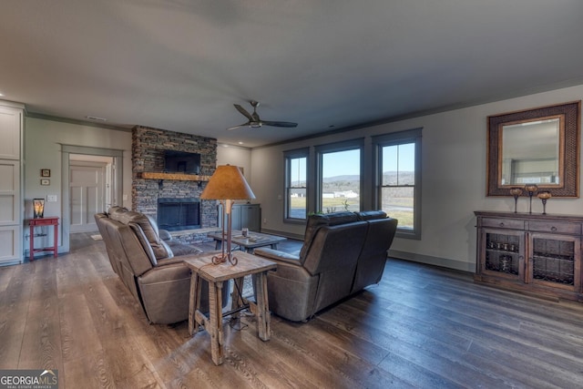 living room featuring ceiling fan, ornamental molding, a fireplace, and dark hardwood / wood-style flooring