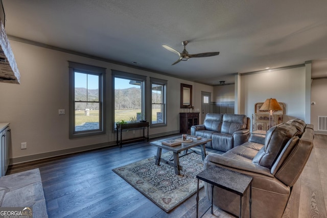 living room with hardwood / wood-style flooring, ornamental molding, a mountain view, and ceiling fan