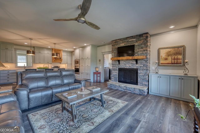 living room with ceiling fan, a fireplace, dark hardwood / wood-style flooring, and sink