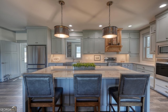 kitchen with appliances with stainless steel finishes, decorative light fixtures, light stone countertops, and a kitchen island