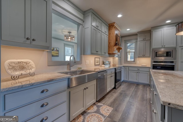 kitchen with sink, a wealth of natural light, light stone countertops, and appliances with stainless steel finishes