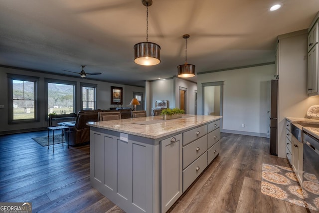 kitchen with dark wood-type flooring, gray cabinets, hanging light fixtures, light stone counters, and a kitchen island