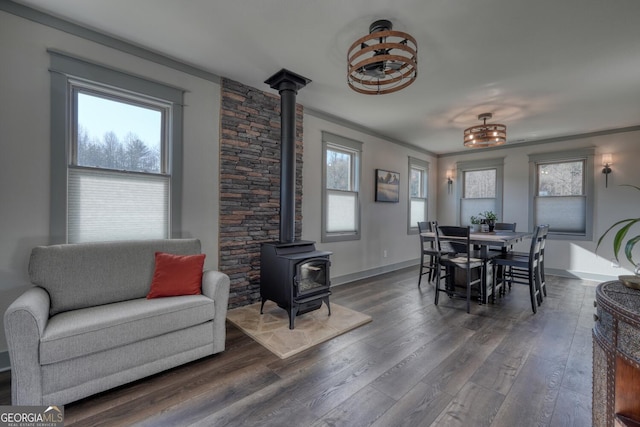 dining area featuring dark hardwood / wood-style flooring, ornamental molding, and a wood stove