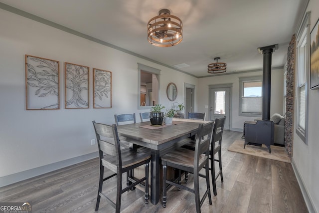 dining room featuring crown molding, wood-type flooring, and a wood stove