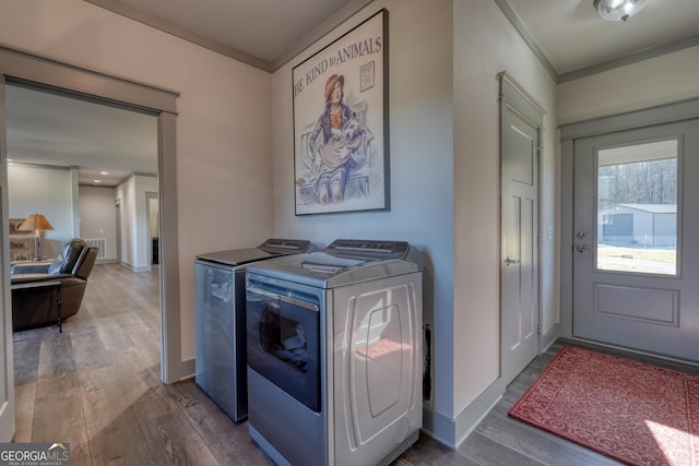 washroom featuring wood-type flooring, washing machine and clothes dryer, and crown molding