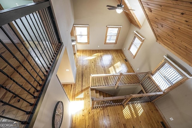 stairs featuring hardwood / wood-style floors, high vaulted ceiling, and ceiling fan