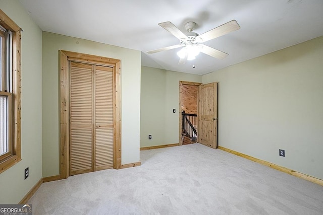 unfurnished bedroom featuring light colored carpet, ceiling fan, and a closet