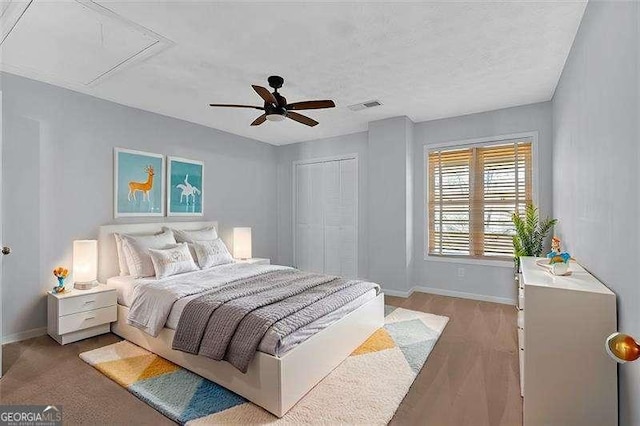 bedroom featuring light hardwood / wood-style flooring, ceiling fan, and a closet