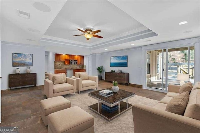 living room with crown molding, a tray ceiling, and ceiling fan