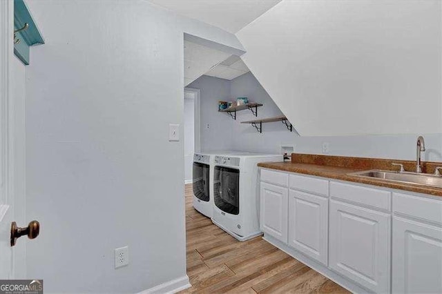 laundry room with washing machine and dryer, sink, and light hardwood / wood-style flooring