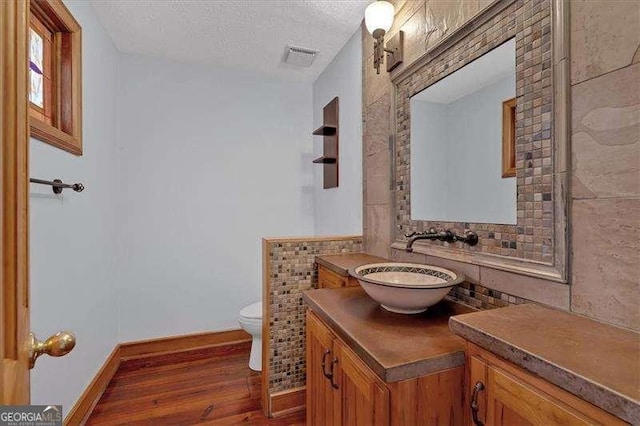 bathroom featuring hardwood / wood-style flooring, vanity, toilet, and a textured ceiling