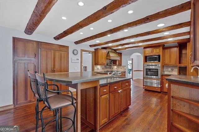 kitchen featuring sink, dark wood-type flooring, custom range hood, built in microwave, and oven