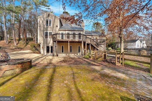 back of property with a deck and a lawn