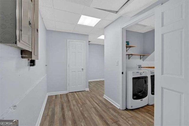 clothes washing area with washer and clothes dryer and light hardwood / wood-style flooring