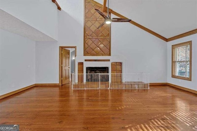 unfurnished living room featuring hardwood / wood-style floors, crown molding, high vaulted ceiling, and ceiling fan