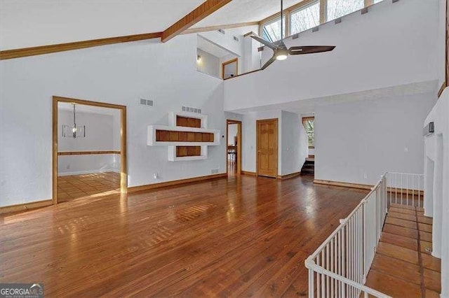 unfurnished living room featuring beamed ceiling, wood-type flooring, high vaulted ceiling, and ceiling fan