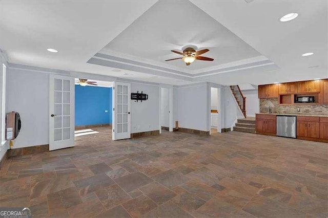 unfurnished living room with a raised ceiling, crown molding, ceiling fan, and french doors