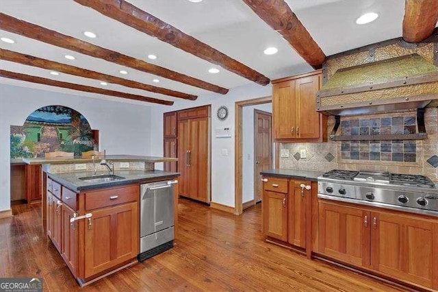 kitchen featuring a kitchen island with sink, custom exhaust hood, stainless steel appliances, and light wood-type flooring