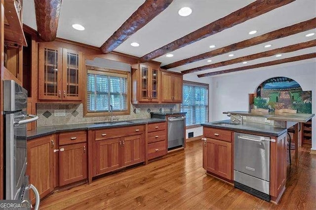 kitchen with sink, light hardwood / wood-style flooring, stainless steel appliances, and an island with sink