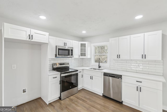 kitchen with white cabinetry, sink, light hardwood / wood-style flooring, and appliances with stainless steel finishes