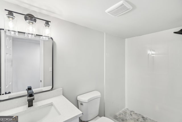 bathroom featuring tiled shower, vanity, and toilet