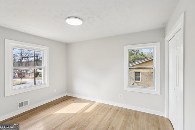 spare room featuring plenty of natural light and light hardwood / wood-style floors