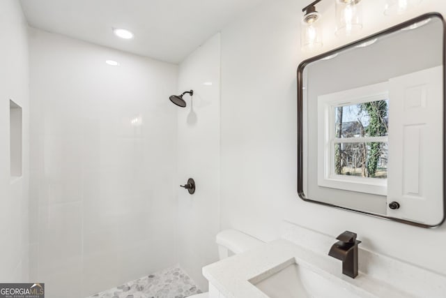 bathroom with vanity, a tile shower, and toilet