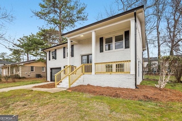 split foyer home featuring cooling unit, a garage, a front yard, and covered porch