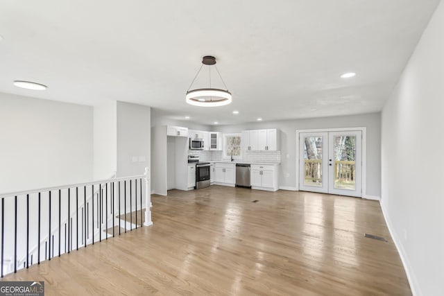 unfurnished living room featuring french doors and light hardwood / wood-style floors