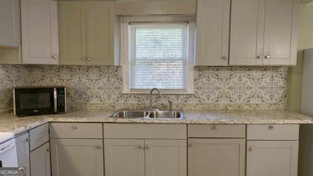 kitchen featuring light stone counters, sink, backsplash, and white cabinets