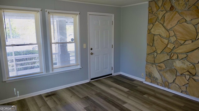 foyer with dark wood-type flooring, a healthy amount of sunlight, and ornamental molding