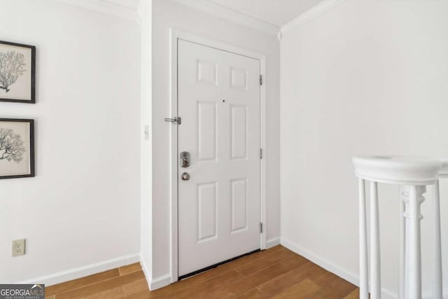 foyer featuring crown molding, wood-type flooring, and a textured ceiling