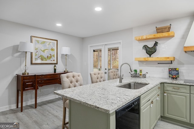 kitchen with black dishwasher, sink, green cabinets, light stone counters, and kitchen peninsula