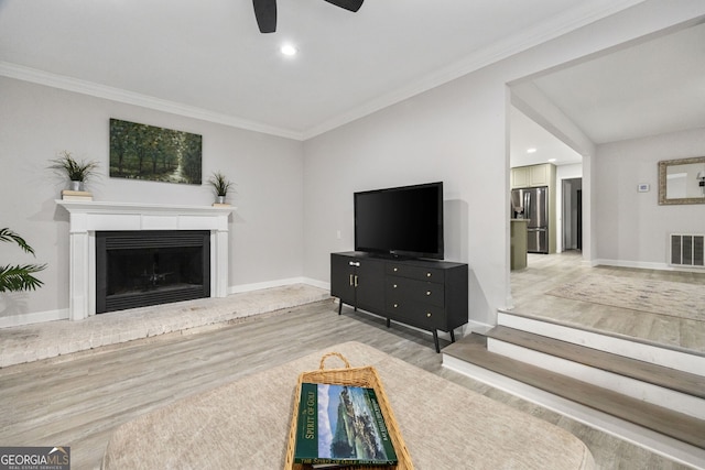 living room featuring ornamental molding, ceiling fan, and light hardwood / wood-style floors