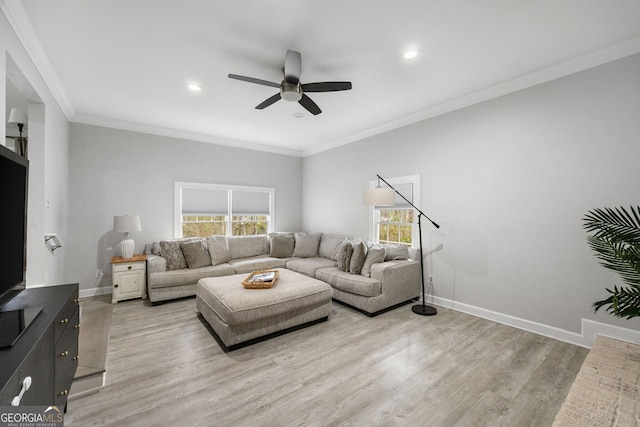 living room featuring ornamental molding, light hardwood / wood-style floors, and ceiling fan