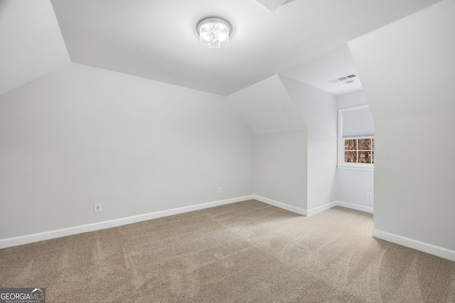 bonus room with vaulted ceiling and light colored carpet