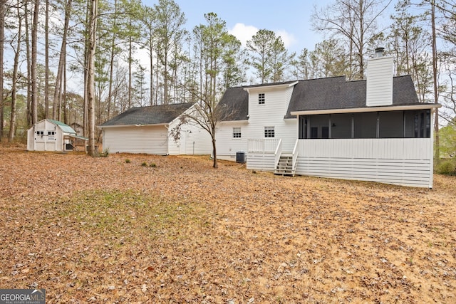 rear view of property featuring a sunroom and a storage shed