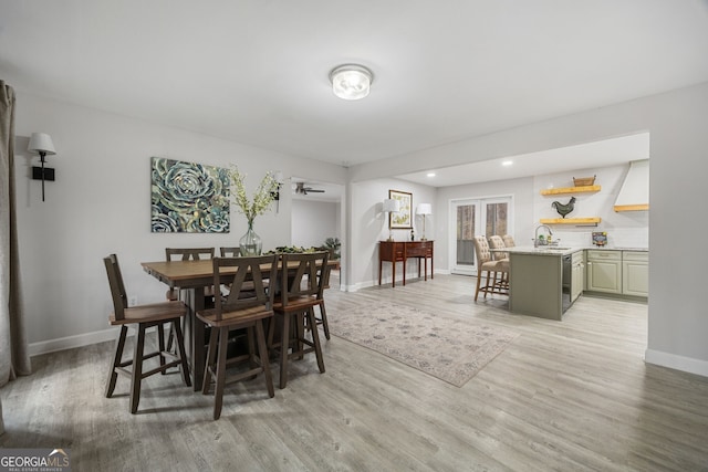 dining room with french doors, sink, and light hardwood / wood-style flooring