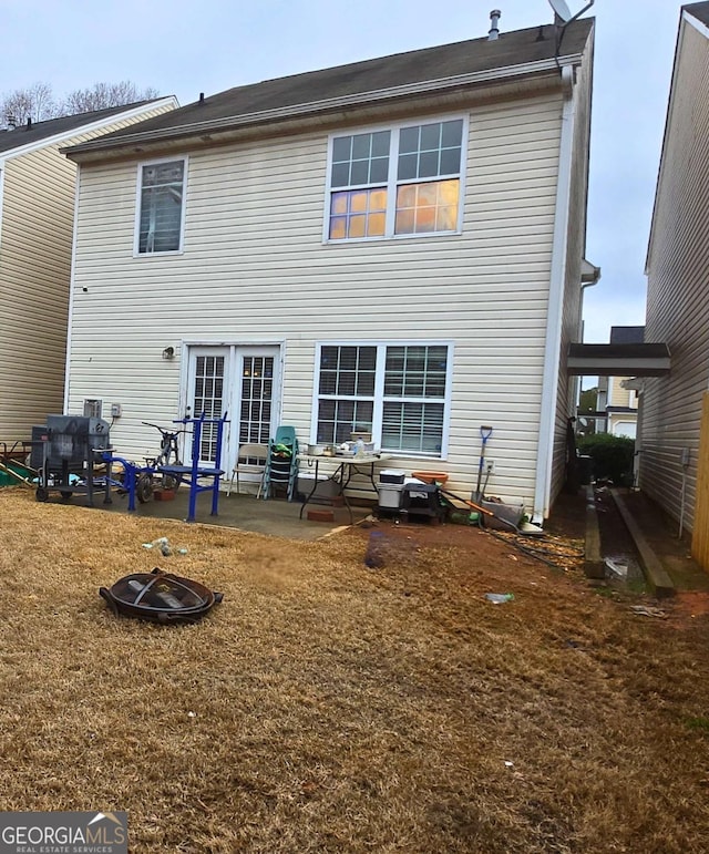 rear view of property with french doors, a patio area, a fire pit, and a lawn