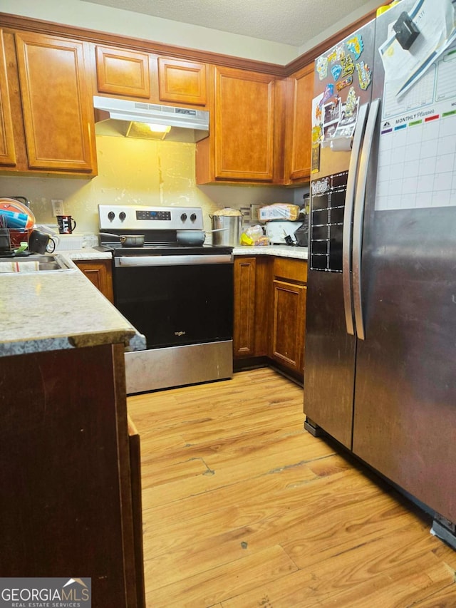 kitchen featuring sink, light hardwood / wood-style flooring, stainless steel appliances, and a textured ceiling