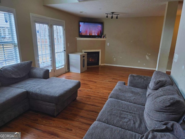 living room featuring dark hardwood / wood-style flooring, track lighting, and a textured ceiling