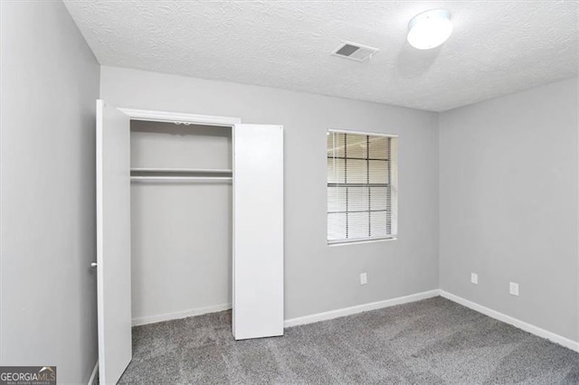 unfurnished bedroom with carpet floors, a closet, and a textured ceiling