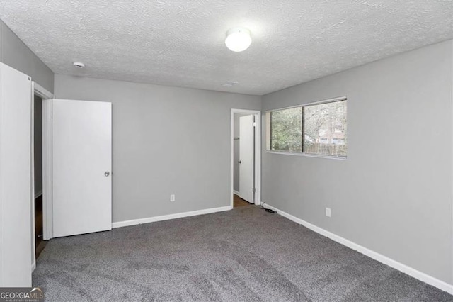 empty room featuring a textured ceiling and dark carpet