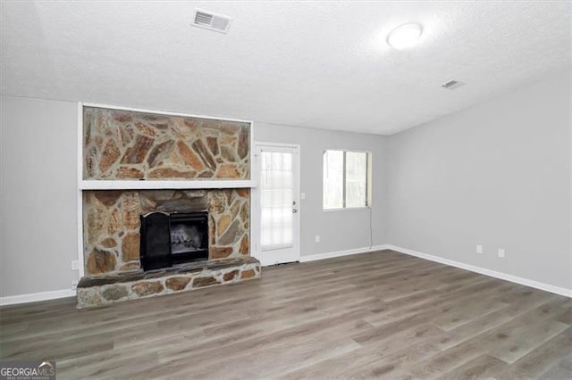 unfurnished living room featuring a fireplace, hardwood / wood-style floors, and a textured ceiling