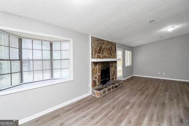 unfurnished living room with wood-type flooring, a fireplace, and a textured ceiling