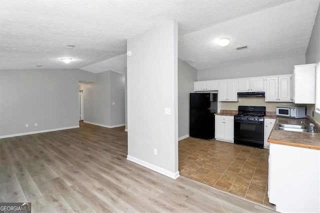 kitchen featuring sink, black appliances, white cabinets, vaulted ceiling, and light wood-type flooring