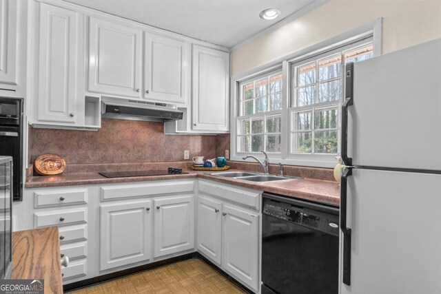 kitchen with sink, white cabinets, backsplash, black appliances, and light parquet flooring