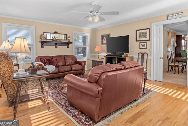 living room with wood-type flooring, ornamental molding, and ceiling fan